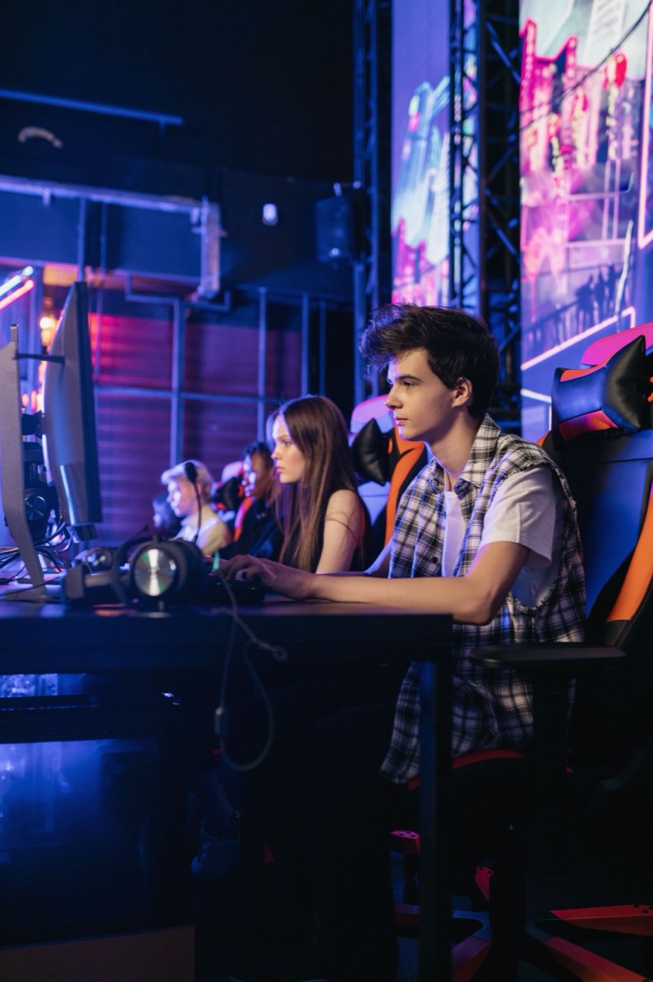 A row of players at monitors in a lit esports venue.